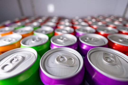 Colorful aluminum can beverage drink refreshment metallic closeup row pattern shiny unopened cold fridge storage variety soft drink energy drink soda carbonated assortment vibrant horizontal