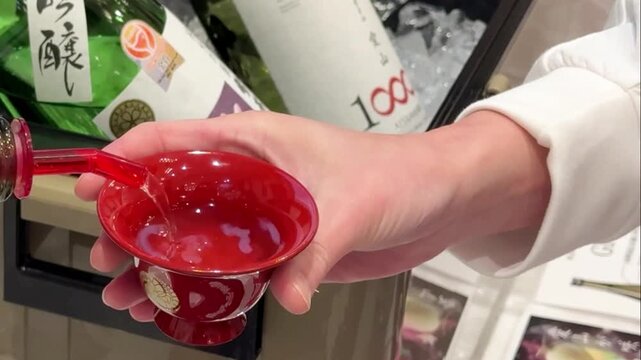 お猪口を持つ女性に盃に日本酒を注ぐ