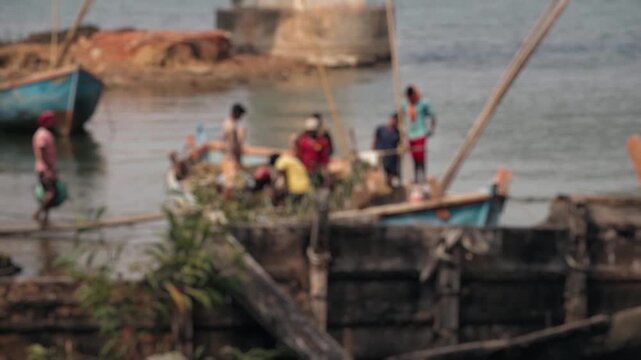 Indian laborers unloading sand from a wooden boat onto a riverbank, manual teamwork and hard physical work reflecting traditional transport, livelihood and village life