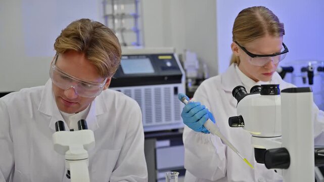 Professional Female Biologist Use Pipette For Science Test With Colleague