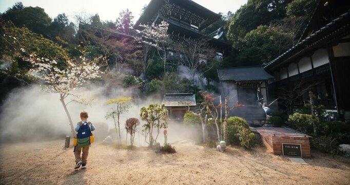 Child with Backpack Exploring Japanese Temple Courtyard in Mist, Wide Slow Motion Shot