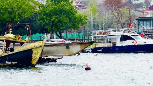 Traditional wooden ottoman sultan boat moored at pier on Golden Horn bay water in Istanbul, Turkey. Passenger vessels line near Bosphorus strait, maritime transportation and coastal urban scene.