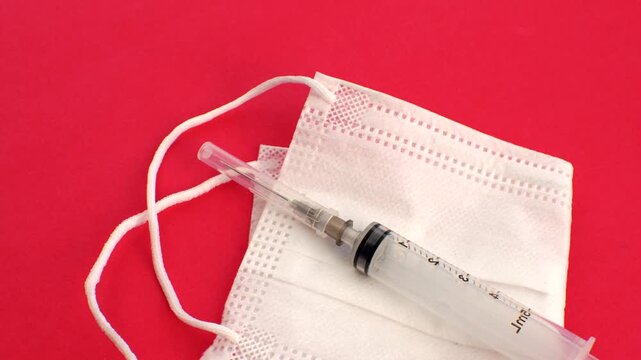Syringe and white mask, symbols of care and prevention in a clean and impactful composition. Close-up of a syringe and white mask, essential elements in the fight against diseases