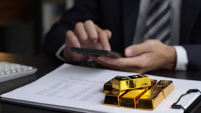 Asian businessman using smartphone trading gold bar on online market