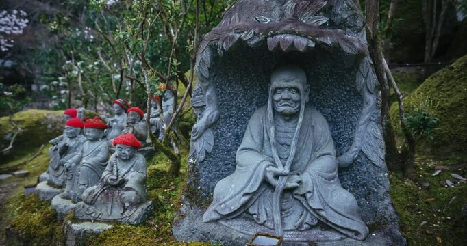 Old Stone Rakan Statues with Red Hats in Mossy Japanese Garden - Steady Cam