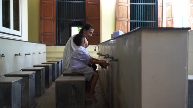 A series of photos showing a heartwarming moment of an adult teaching and helping a young Muslim boy perform Wudu (Islamic ritual purification) at a mosque's ablution area before prayer.