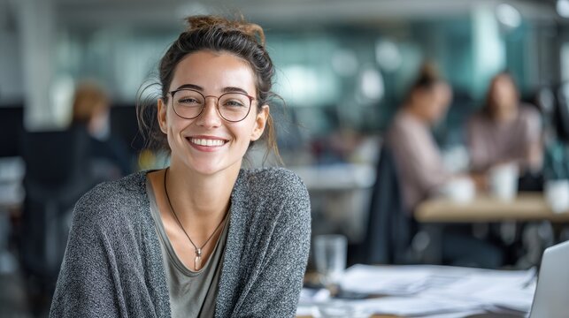 43.Candid business portrait of a woman in glasses smiling during a meeting, light filled open office, clean desk with documents and laptop, friendly and collaborative work culture concept