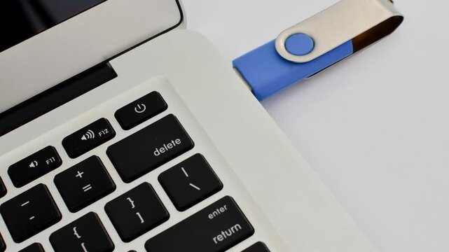 Detail of a USB drive next to a laptop, representing portable technology and fast data transfer.