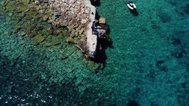 People standing on a small pier in crystal clear water