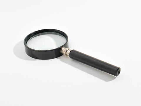 Classic magnifying glass with black handle isolated on white background high angle side view