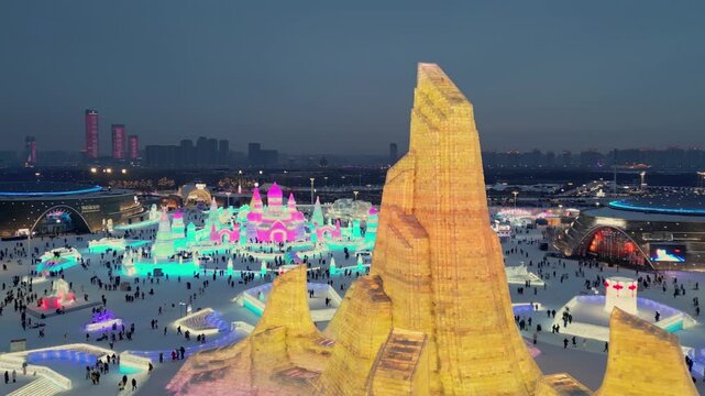 Evening illuminated ice towers of ice and snow city in Harbin. Frozen spires glow with lights, China