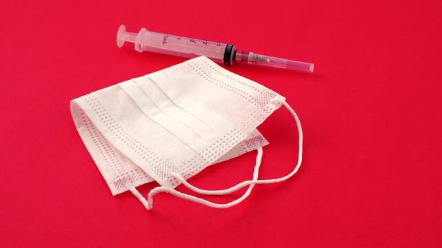 Syringe and white mask, symbols of care and prevention in a clean and impactful composition. Close-up of a syringe and white mask, essential elements in the fight against diseases
