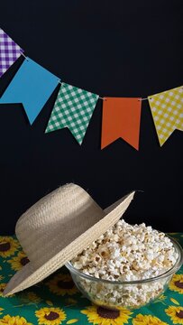 A bowl of popcorn on the table and colorful flags in the background. Decoration for a Brazilian June festival. Arrai&aacute;.