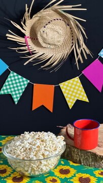 A bowl of popcorn on the table and colorful flags in the background. Decoration for a Brazilian June festival. Arrai&aacute;.