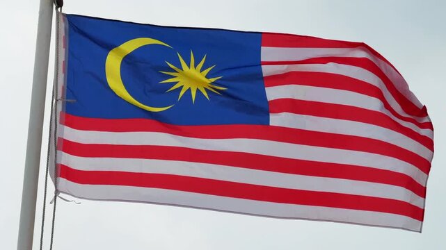 Close up of Malaysian National Flag Jalur Gemilang Waving in the wind against overcast sky