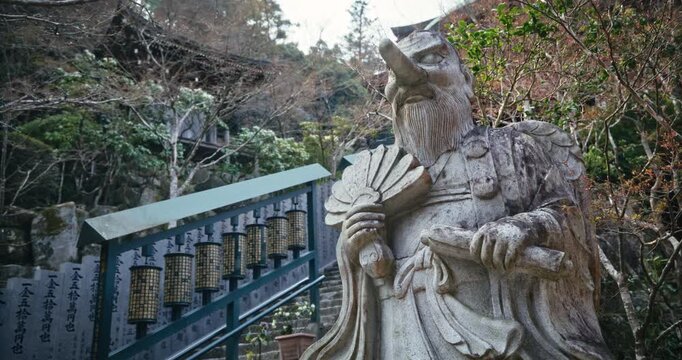 Ancient Stone Deity Statue with Fan at Hiroshima Temple Stairway - Low, Steady Cam Shot