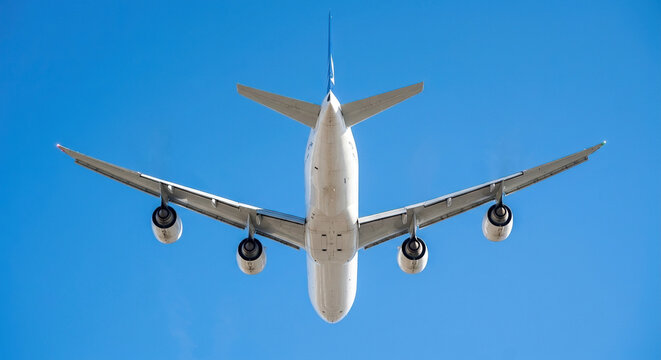 Large four-engine passenger airplane flying in clear bright blue sky