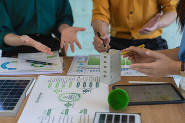 Fototapeta premium A close-up image of expert hands working on ESG concepts using solar cell and wind turbine models. The group of engineers is planning a sustainable green energy city.