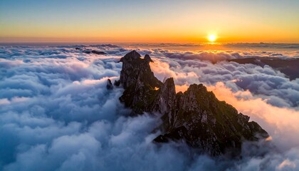 Fototapeta premium Breathtaking aerial view of rugged mountain peaks rising above a thick sea of fluffy white clouds during a beautiful golden sunrise light.
