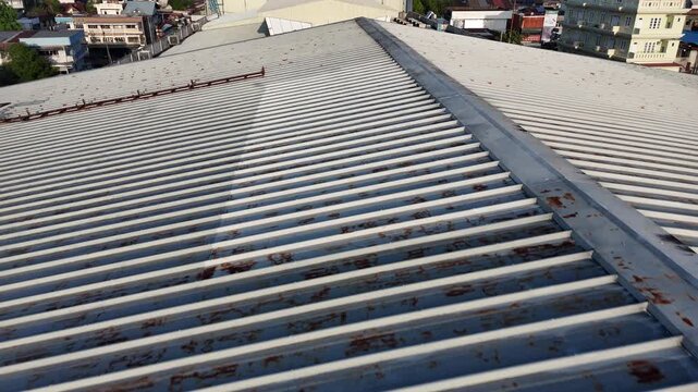 A view from the top of a corrugated metal roof with rusted panels and industrial-style urban buildings.