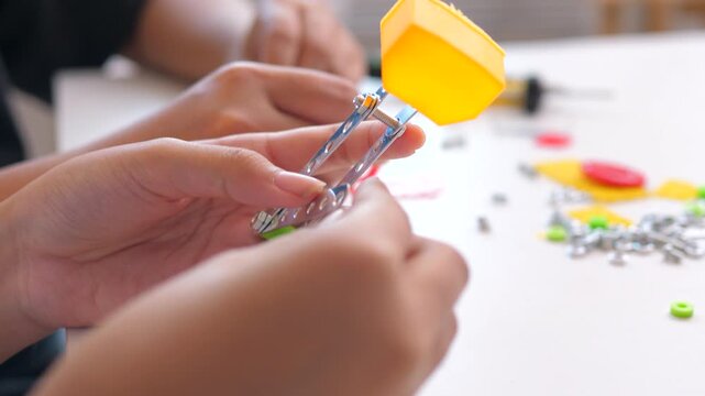 Close up of child hands assembling 3D printed robot model on table. Concept of STEM education, robotics learning, creativity, and technology development