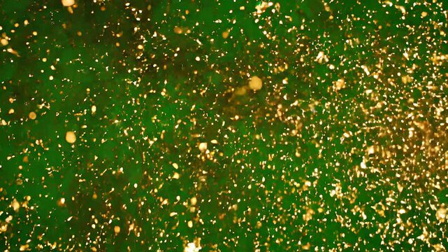 Dynamic golden sparks burst and explode across a vibrant green screen background, ideal for motion graphics and visual effects