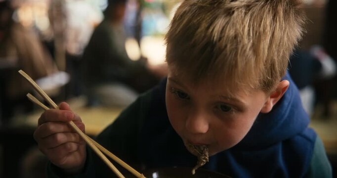 Boy Eating Noodle Soup with Chopsticks in Hiroshima Restaurant - closeup