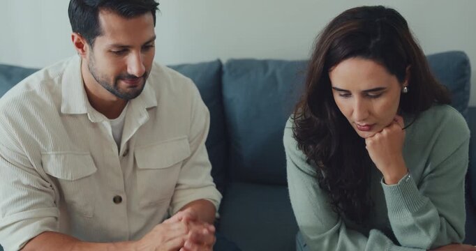 Unhappy young Latin man and woman discussing finance debt and bankruptcy on the couch at home. Marriage divorce difficulty, serious relationship separation problem, couple counseling therapy concept.