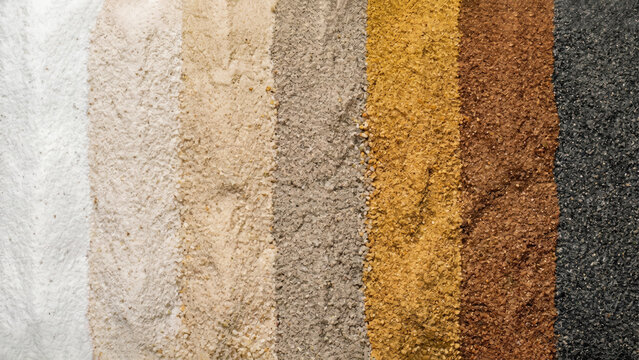 Seven vertical bands of distinct sand types side-by-side. Granular textures range in color from white, transitioning through tan, gray, yellow, and brown, to black.