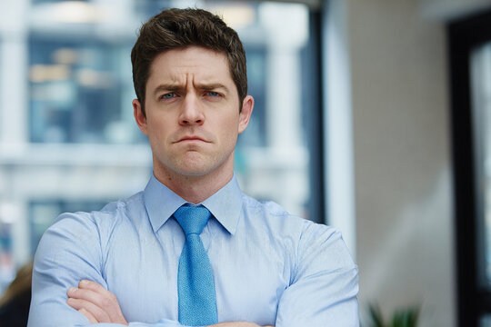 Serious business manager with crossed arms in a modern office under bright professional lighting