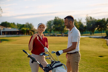 Naklejka premium Happy couple choosing a golf club on golf course.