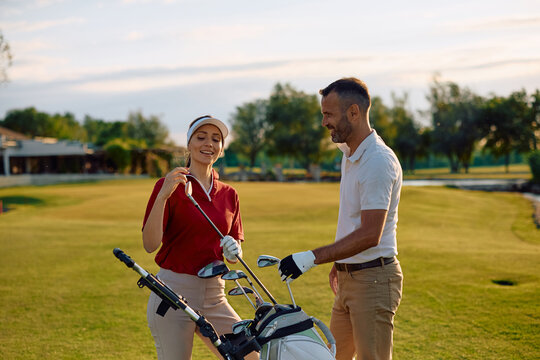 Happy couple choosing a golf club on golf course.