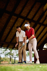 Fototapeta premium Full length of golfing couple during practice session at golf driving range.