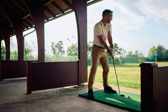 Full length of a man practicing his golf swing at driving range.