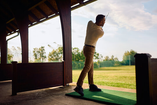 Male golfer during practice session at golfing driving range.
