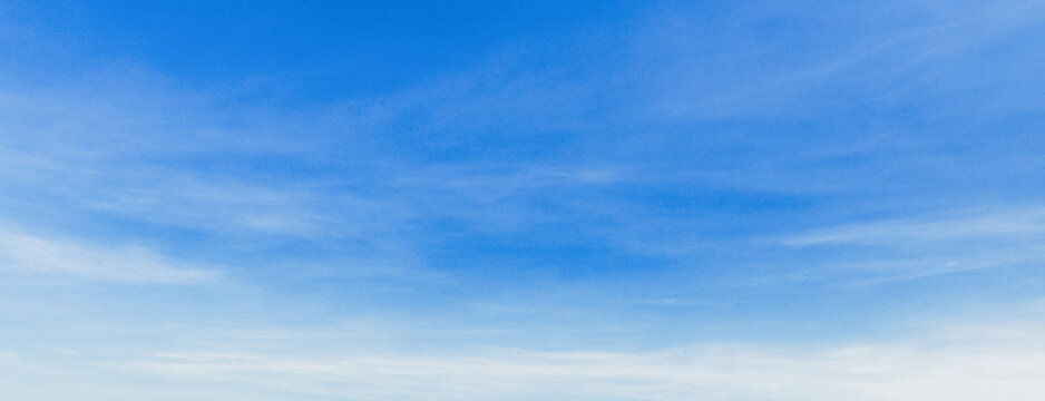 Soft clouds drift across a vast, clear blue sky