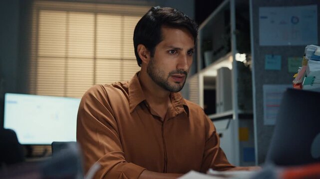 Overworked Latin businessman receiving extra paperwork from boss at desk in dark night office. Working late overload, deadline burnout, heavy overtime stress, corporate business problem concept.