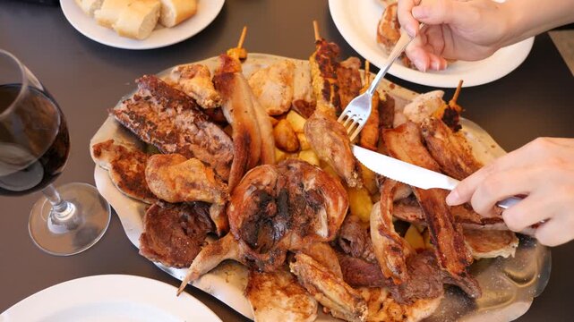 Quails cooked on the grill and served on a large plate, against the background of female hands with with cutlery. High quality 4k footage