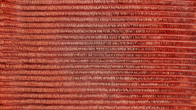 rust corduroy fabric texture background with horizontal ribbed velvet wales close up