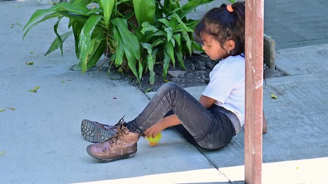 Latina girl playing on the patio floor with her toy chick