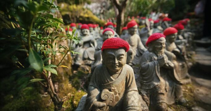 Stone Jizo Statues with Red Knit Caps in Temple Garden Japan - low shot