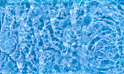 Blue water surface with ripples and sunlight reflections abstract summer background. Summer beauty concept.Top view. Copy space