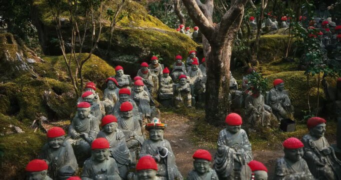 Rows of Stone Rakan Statues with Red Knitted Caps in Forest Garden In Japan