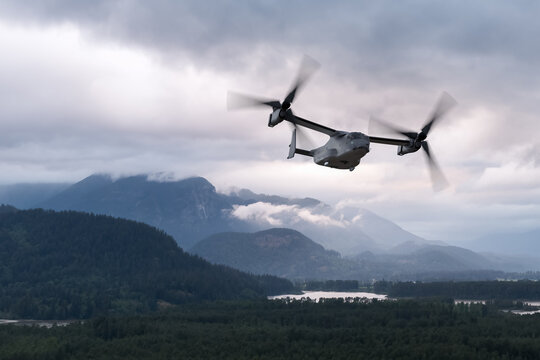 Tiltrotor Military Transport Aircraft Flying Over Misty Mountains Near River in British Columbia Canada Landscape
