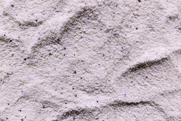 Fototapeta premium Top view close up of white laundry detergent powder texture with blue and yellow speckles