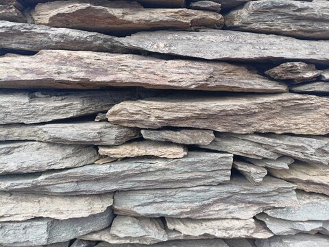 Rough grey stone slate wall texture, horizontal natural stacked flagstone cladding
