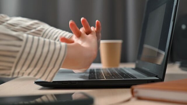 A person engages in typing on a laptop while performing various wrist and hand movements. This activity takes place in an office setting, promoting wellness during work hours