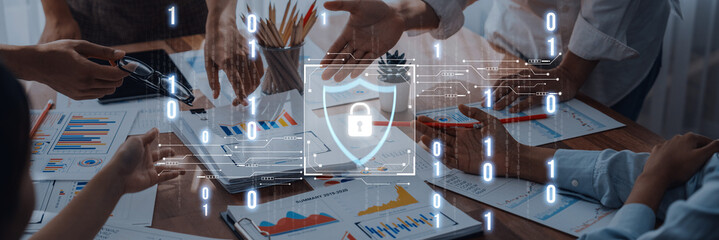 Business professionals shake hands over financial reports while security graphics display. This...