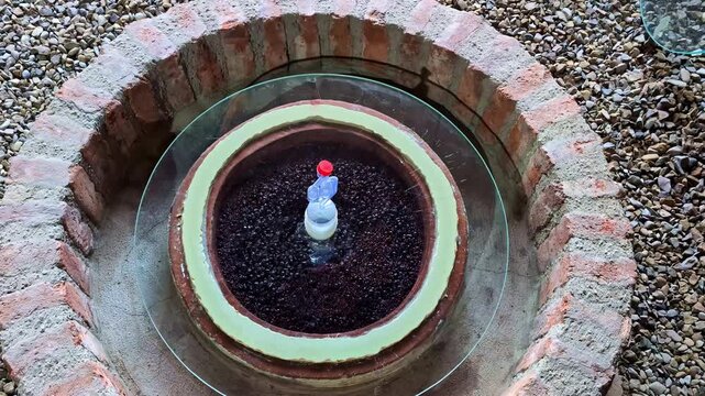 Garden water feature circular brick-walled base dark clay pot filled with pebbles decorative item
