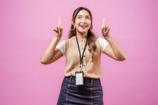 Joyful young Asian woman in a brown shirt pointing to the copy space above her.
